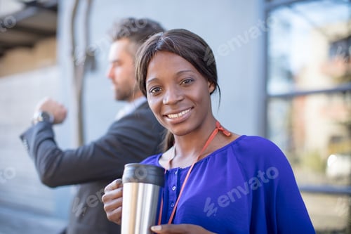 Preview: Portrait of smiling businesswoman with coffee mug and businessman in background