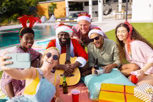 Preview: Portrait of diverse friends with santa hats taking selfie in garden at christmas