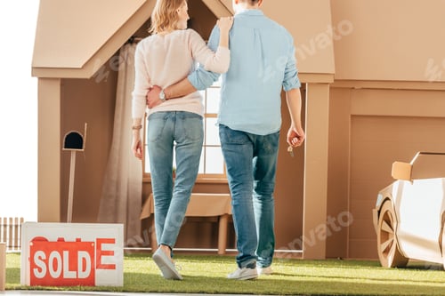 Preview: rear view of newlyweds walking to their new cardboard house