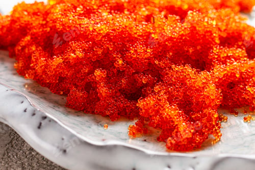 Preview: orange Tobiko flying fish caviar, on a light blue plate, caviar for rolls and sushi, close-up,