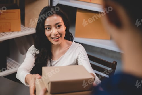 Preview: Packing goods for delivery to customer, parcel in hand of owner e-business woman to delivery man
