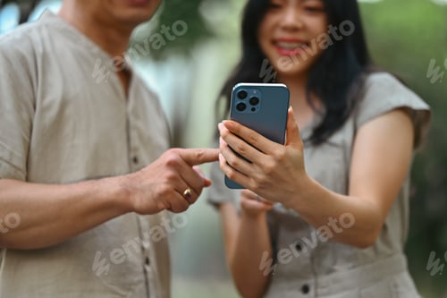 Preview: Cheerful young woman and father watching video content online on mobile phone