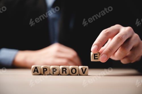 Preview: Closeup of wooden cubes with letters and word approve on table with unrecognized man