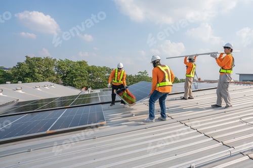 Preview: Men technicians carrying photovoltaic solar moduls on roof.
