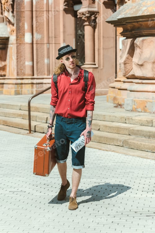 Preview: tourist with travel newspaper and vintage suitcase walking in city