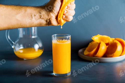 Preview: An anoymous hand is squeezing an orange to glass