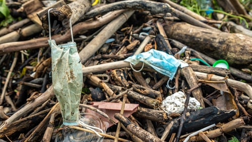 Preview: Medical waste mask and plastic gloves garbage trash on sea shore. Covid19