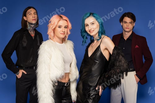 Preview: nonbinary people in stylish clothes looking at camera while posing isolated on blue