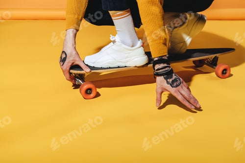 Preview: low section view of skateboarder in white sneakers on longboard, on yellow