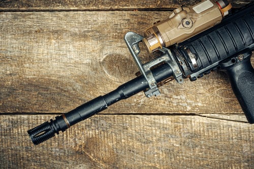 Preview: Barrel of modern automatic rifle on wooden surface