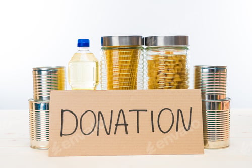 Preview: different food with cardboard donation sign on wooden table isolated on white, donation concept