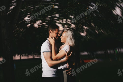 Preview: Young happy couple in love kissing in the night Park. Photo with flash effects