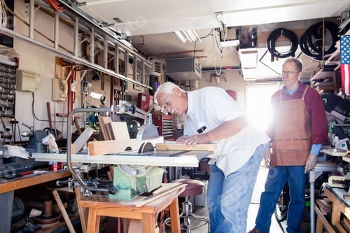Preview: Senior men sawing woodblock in carpentry workshop