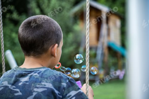 Preview: Boy Blowing Bubbles in Backyard on a Sunny Day