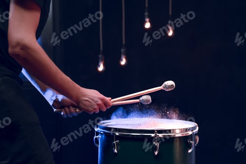 Preview: The drummer plays with mallets on floor tom in dark room.