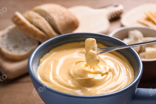Preview: Dipping bread into pot with cheese fondue on table, closeup