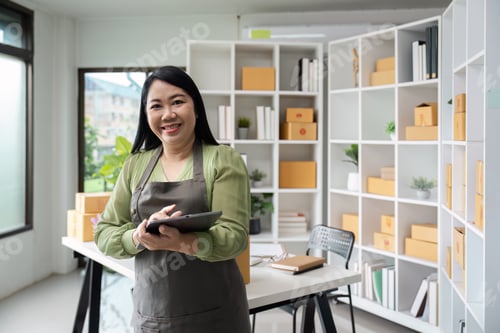 Preview: Confident Female Small Business Owner in Modern Office with Shelves of Products and Tablet in Hand