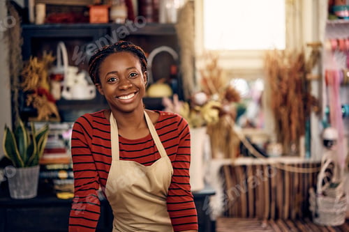 Preview: Happy African American woman working as florist at flower shop and looking at camera.