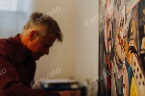 Preview: Old man artist painting oils in his studio.