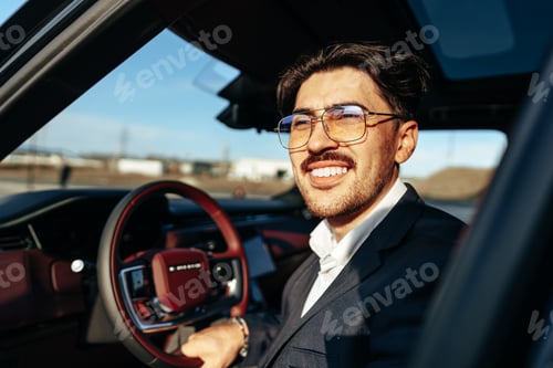 Preview: Young businessman in elegant suit driving luxury car