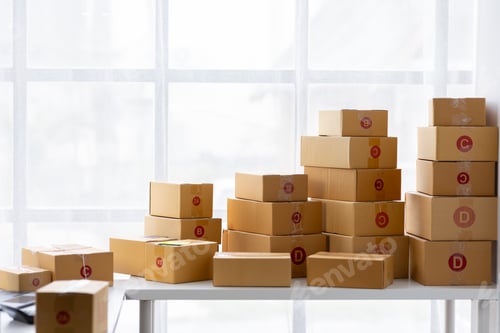 Preview: Parcel boxes on shelf and color shopping bags placing near laptop on table. SME business on shopping