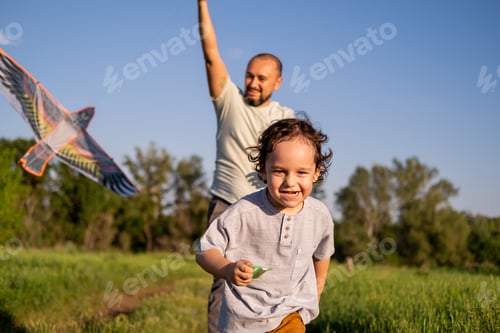 Preview: Father and son are running at sunset and flying a kite. Happy dad and baby.