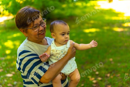 Preview: Grandmother holding her granddaughter in a green park