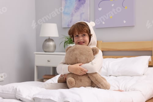Preview: Little boy with teddy bear on bed at home