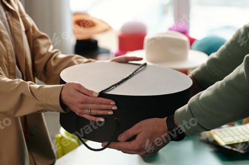 Preview: Close-up of young female clerk of craft shop passing box to client