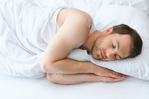 Preview: Handsome man sleeping under soft blanket in bed at home