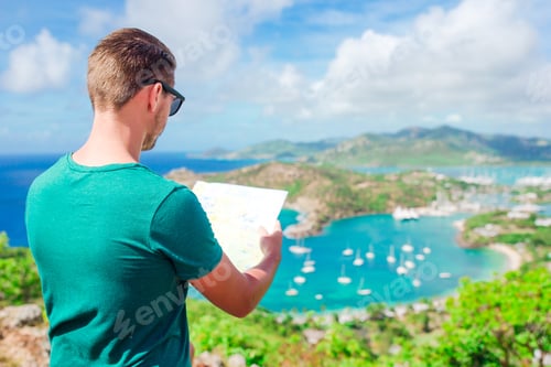 Preview: Young tourist man with map background of English Harbor from Shirley Heights, Antigua, paradise bay