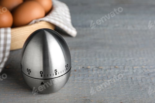 Preview: Kitchen timer and eggs on grey wooden table. Space for text