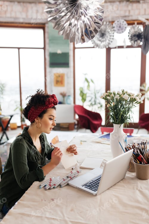 Preview: Young gorgeous woman with dark curly hair sitting at the table t