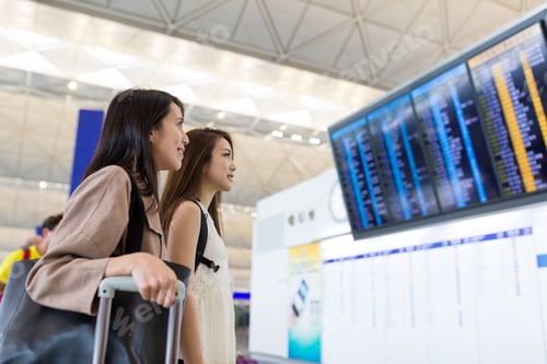 Preview: Friends looking on the flight number in airport
