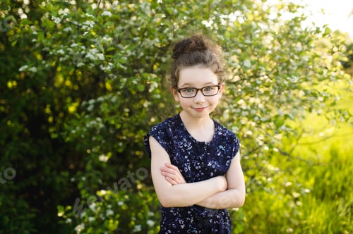 Preview: Portrait of girl wearing eye glasses in field with blossoming trees