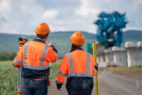 Preview: Survey team is working with a theodolite and road construction plans.