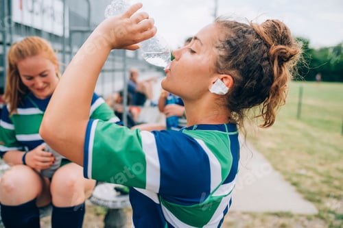 Preview: Young rugby player hydrating during a break at the game.