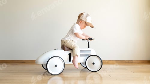 Preview: Toddler driving beige retro car. Happy small boy sitting on vintage toy car.