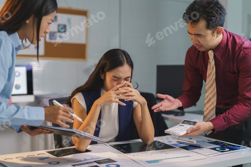 Preview: Asian businesswoman feeling stressed while her colleagues are scolding her about financial reports,