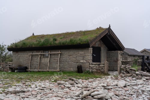 Preview: a little stone structure with a green roof, with some rocks in the foreground