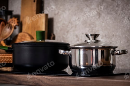 Preview: Steel pots on induction hob on cozy modern kitchen with cooking utensils