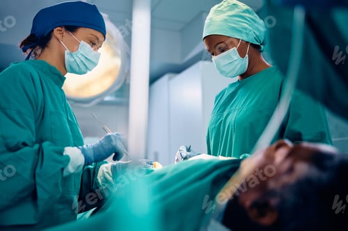 Preview: Black female surgeon and nurse cooperating during the surgery at clinic.
