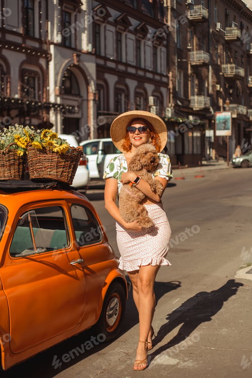 Preview: A young beautiful woman in sunglasses and hat walks around the city on a summer day holding her pupp