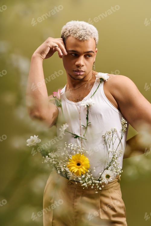 Preview: Confident young man in tank top poses with flowers in stylish studio setting