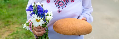 Preview: Grandmother with Ukrainian bread in her hands. Selective focus.