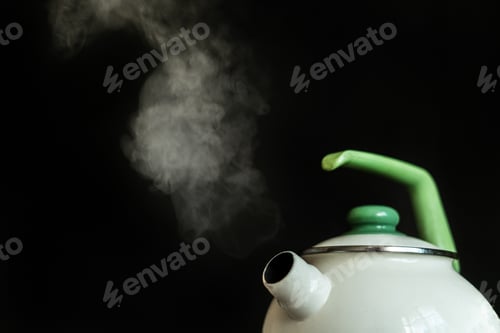 Preview: the kettle with hot boiling water and the steam comes out from it on dark backgrounds