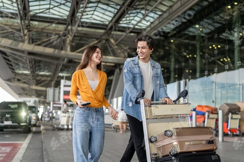 Preview: Asian young couple walk outdoors of airport terminal to boarding gate.