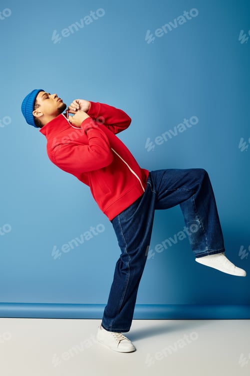 Preview: Stylish young man in beanie poses confidently against a vibrant blue backdrop