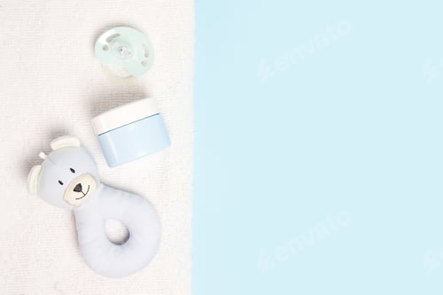 Preview: cosmetic cream for children with toy bear and pacifier on blue background