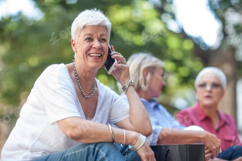 Preview: Senior woman chatting on smartphone in city